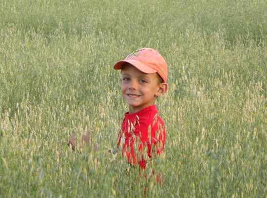 smiling-boy-with-cap-in-the-middle-of-a-field_Woodlands-Forest-School_Community